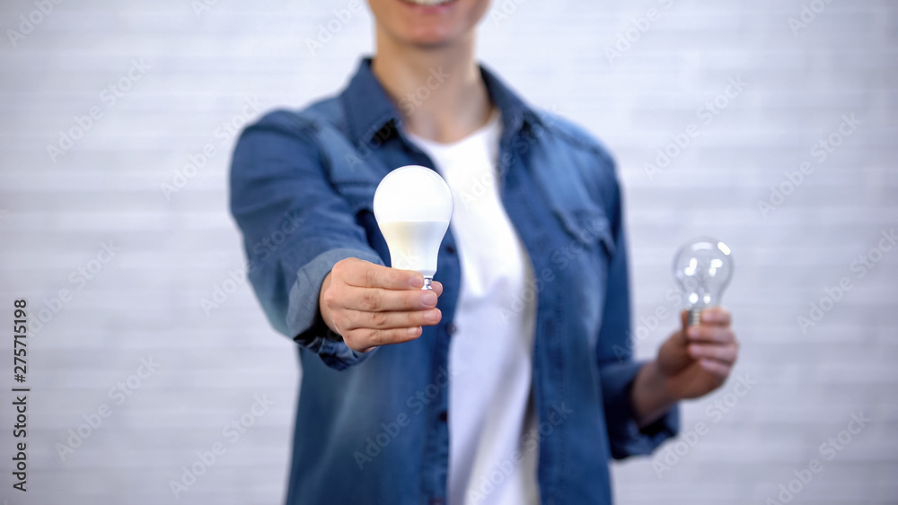 Girl chooses energy saving led bulb instead of incandescent lamp, efficiency - obrazy, fototapety, plakaty 