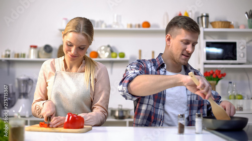 Happy couple cooking dinner together at kitchen, gender equality in housework