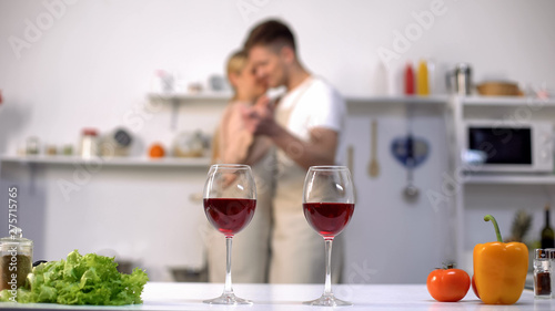 Glasses of wine on table  couple dancing on background  anniversary celebration