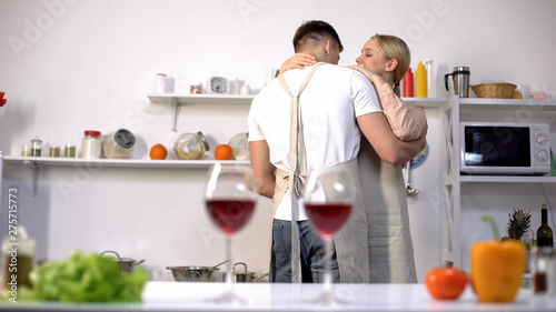 Glasses of wine on table, cute couple dancing on background, romantic evening