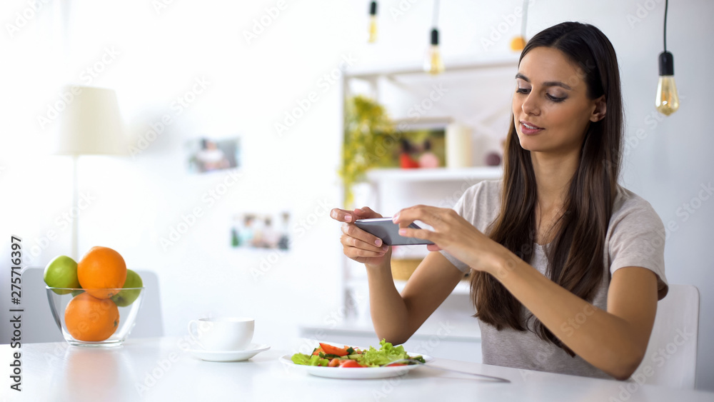 Young food blogger making salad photos on phone, posting in social networks