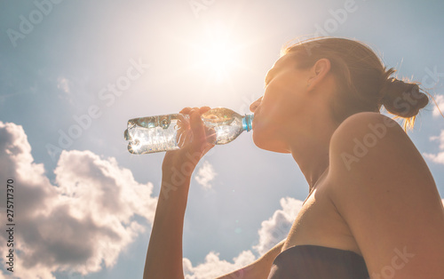 Fotografia, Obraz Young female drinking bottle of water on a hot sunny day.