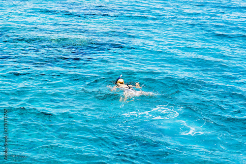 swimming and snorkeling girl in slightly wavy Mediterranean sea water surface in summer vacation warm season time, photography foreshortening from above from drone with empty copy space for text