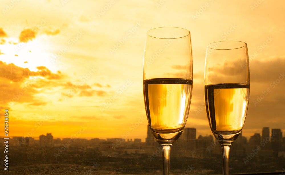 two glasses of champagne on sunset city background 