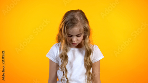 Fotografi Blond curly girl looking down isolated on orange background, feeling guilty