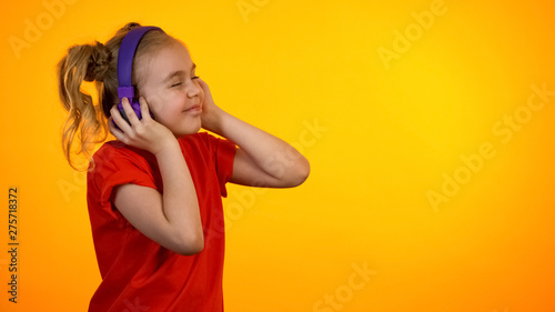 Extremely funny girl in purple earphones listening to favorite song and dancing