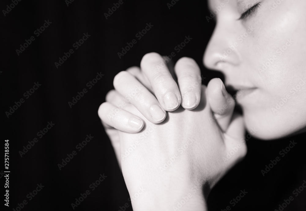 Young woman praying with hands clasped together. 
