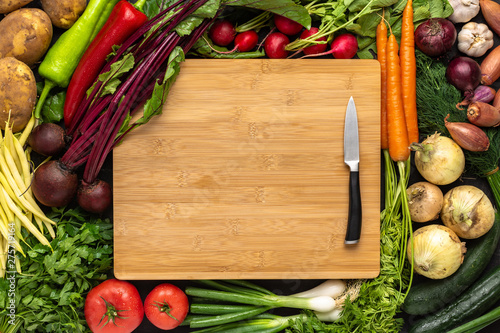 Small Knife on Wooden Cutting Board with Fresh Vegetables Background. Vegetarian Raw Food.