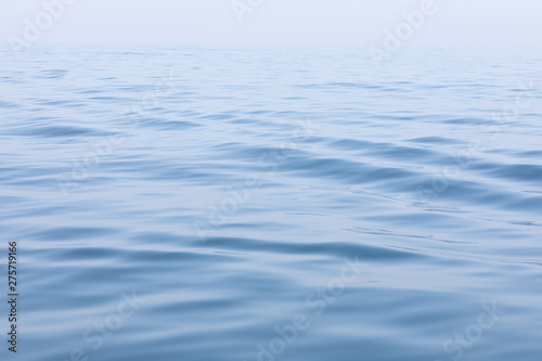 Tranquil and serene ocean surface. Calm and relaxed mirror-like blue sea background.