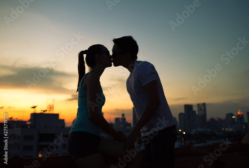 young couple int he city kissing at sunset