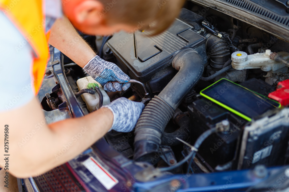 Hands of mechanic repairing the engine of the special keys (wrenches and ratchets). Professional car mechanic in gloves working on the side of the road, field service. Hands of mechanic repairing the engine of the special keys (wrenches and ratchets). Professional car mechanic in gloves working on the side of the road, field service.