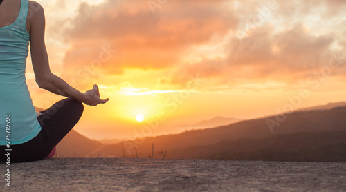 woman practicing yoga on a mountain at sunset