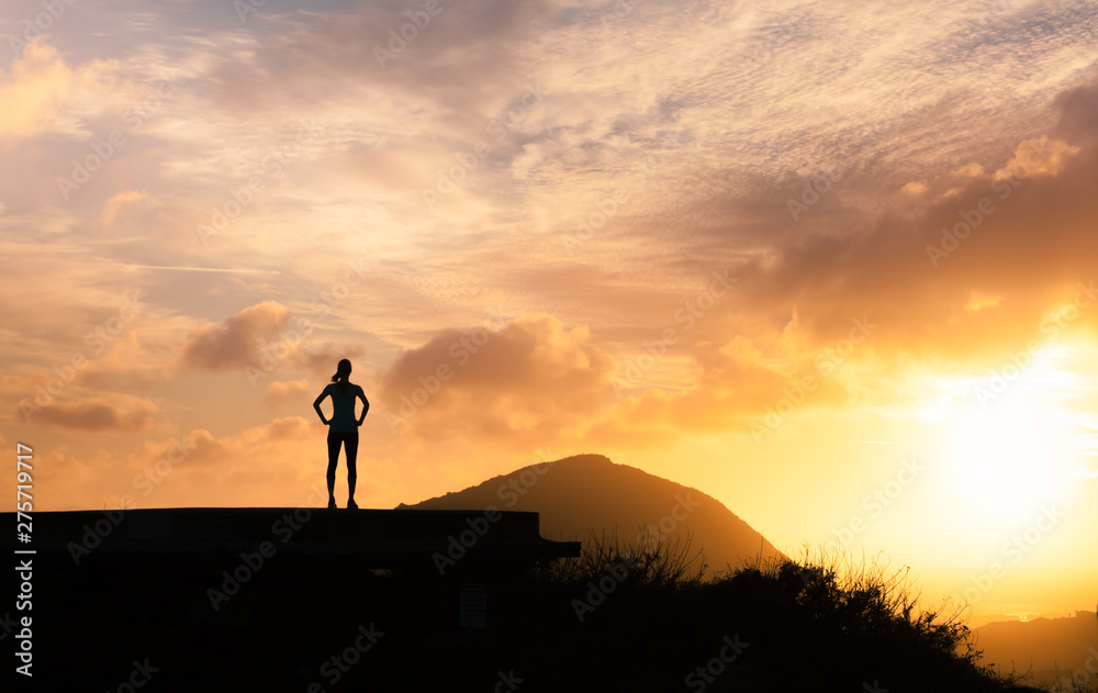 Young active female on a mountain top looking at the sunrise