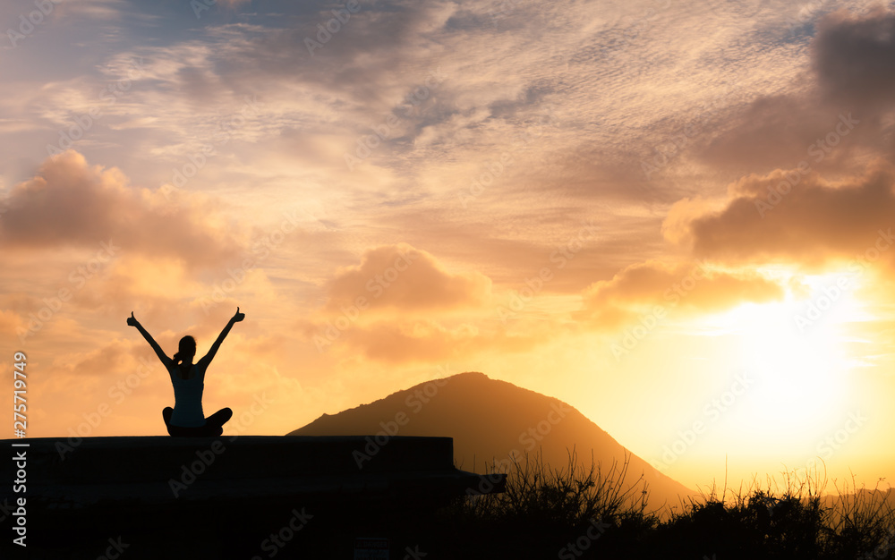Healthy happy active woman with arms up facing the sunset. 