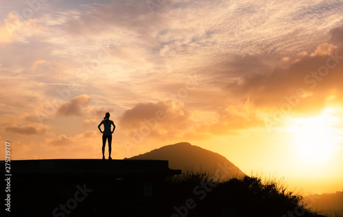Young active female on a mountain top looking at the sunrise