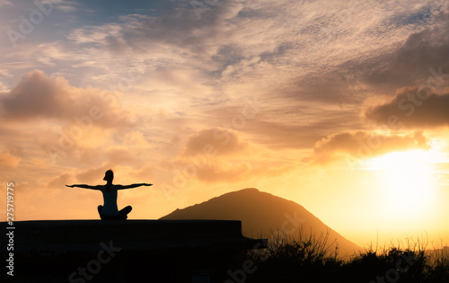 Female meditating facing a beautiful sunrise. 