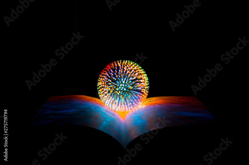 The magic ball of the fortuneteller  the witch  lies on the opened magic book on a black background  copy space