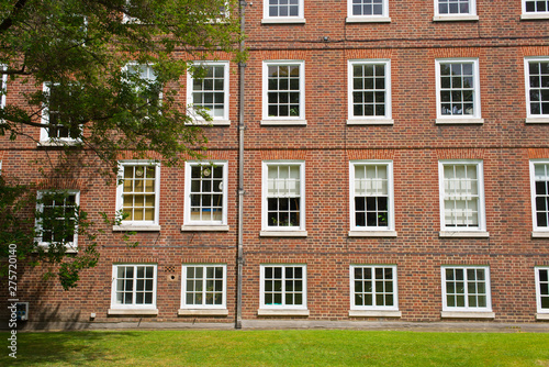 Classic historical Office Building Georgian British English style with white windows, red brick wall and garden in front