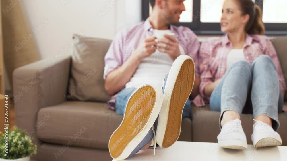 moving, people and leisure concept - feet of couple couple sitting on sofa and drinking coffee at new home moving, people and leisure concept - feet of couple couple sitting on sofa and drinking coffee at new home