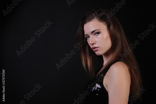 Beautiful portrait of a girl in a shiny vest on a black background photo for text