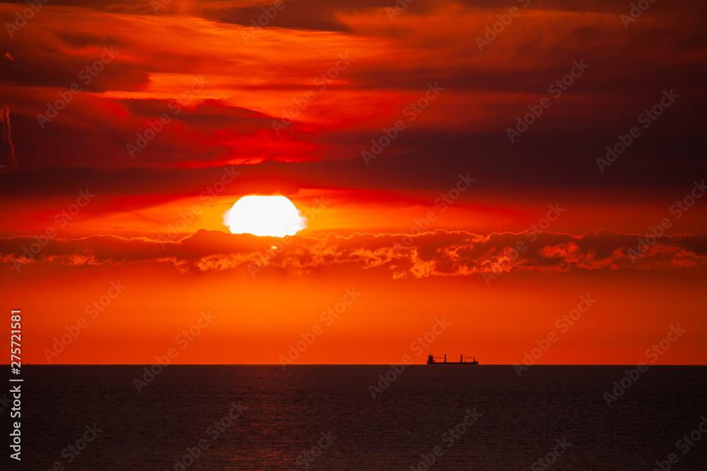 Waterway. Cargo ship on the sea in sunset with  cloud formations in red light