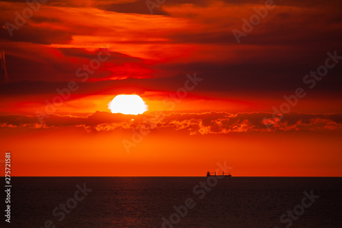 Waterway. Cargo ship on the sea in sunset with cloud formations in red light