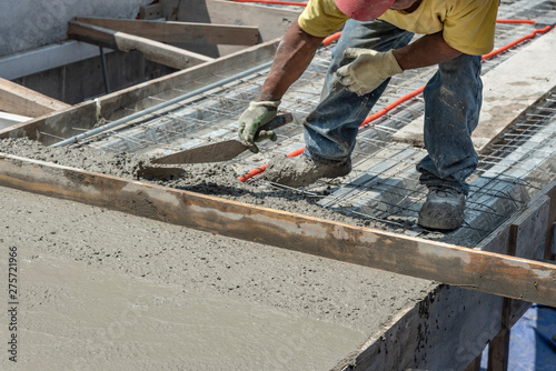 Bricklayer leveling a cement roof. Stretching out to smooth the casted concrete mix 