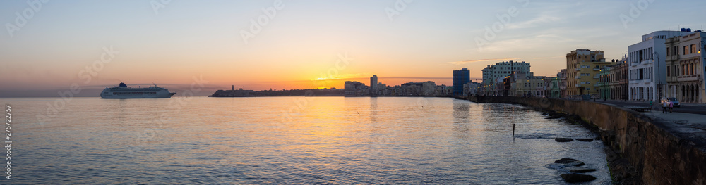 Beautiful Panoramic view of a Big Cruise Ship arriving to the Old Havana City, Capital of Cuba, during a colorful cloudy sunrise.