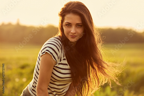 Beautiful thinking smiling young woman looking happy with long bright hair on nature sunset summer background. Closeup © nastia1983