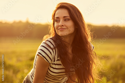 Beautiful calm smiling young woman looking happy with long bright long hair on nature bright sunset summer background. Closeup © nastia1983