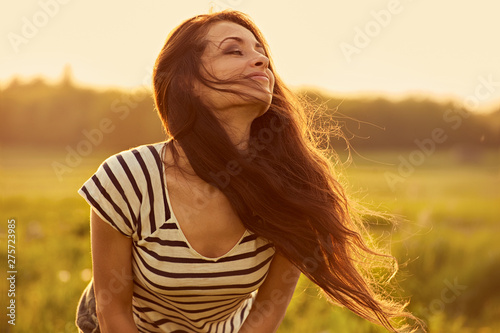 Beautiful smiling young woman looking happy with long amazing bright long hair on nature bright sunset summer background. Closeup toned color portrait. © nastia1983