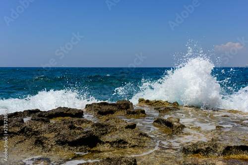  splashing waves crashing against a stone beach