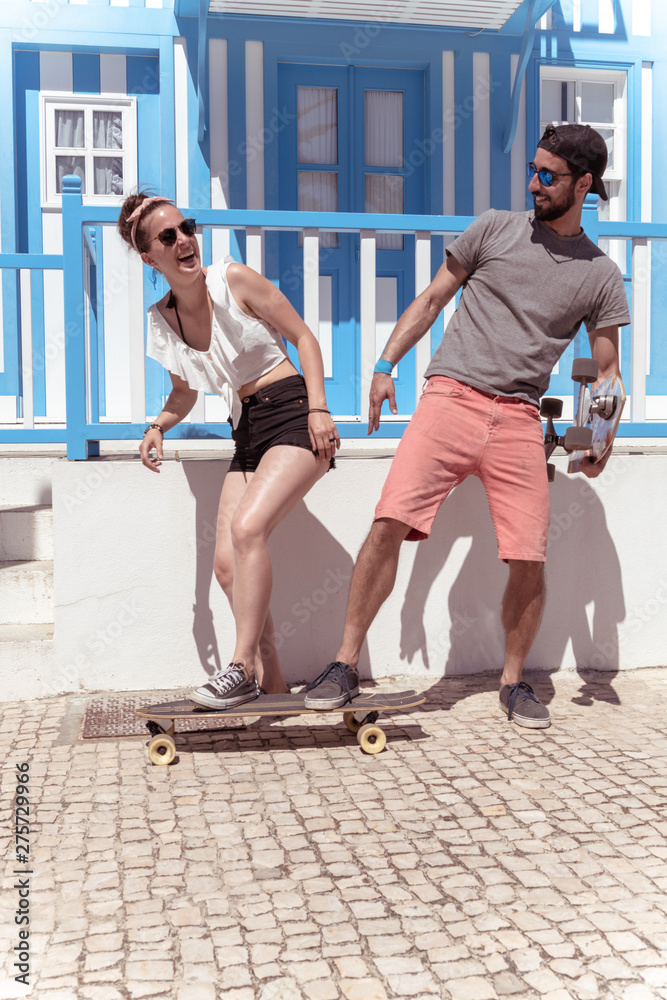 Young active couple enjoying a summer sunny day skateboarding Young active couple enjoying a summer sunny day skateboarding
