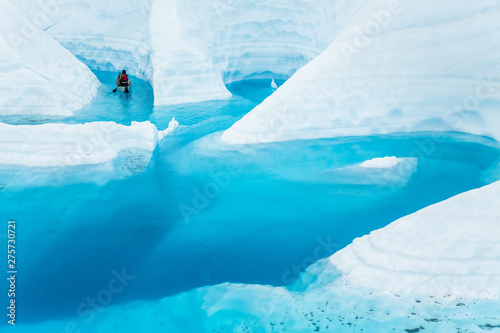 Ice climber boating through winding canyons flooded by glacier water of the Matanuska Glacier in the Alaskan wilderness.