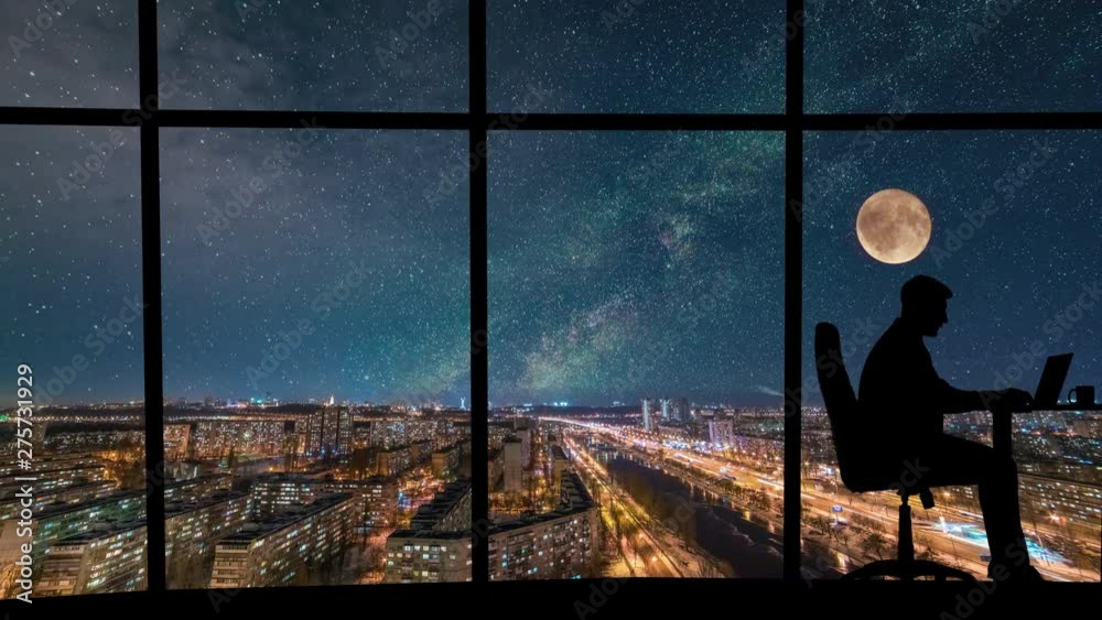 The man working near a panoramic window on a starry sky background