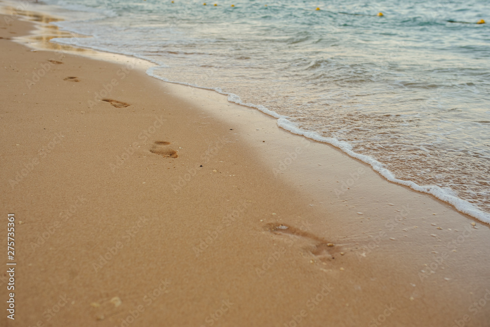 Footprints of human feet on the sand near the water on the beach