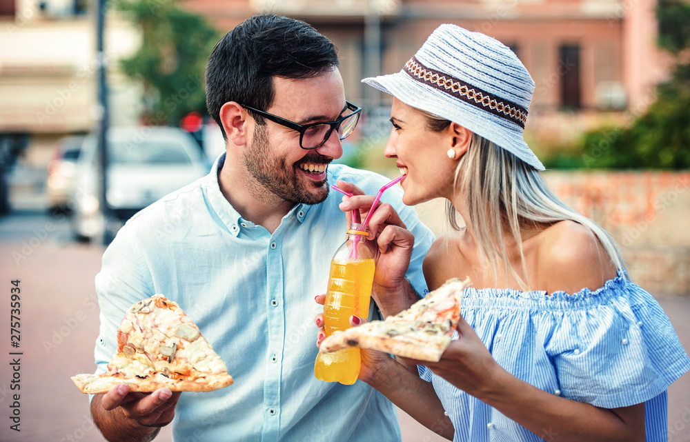 Couple eating pizza outdoors. Dating, consumerism, food, lifestyle concept