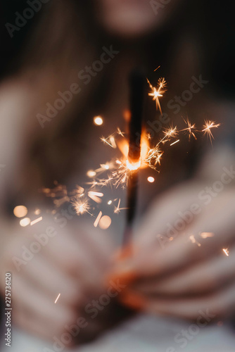 A woman in her twenties with tattoos holding a sparkler in the summer