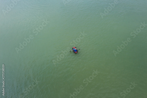 Aerial shot of a quiet green lake with a kayaking in the middle of the water © bqmeng