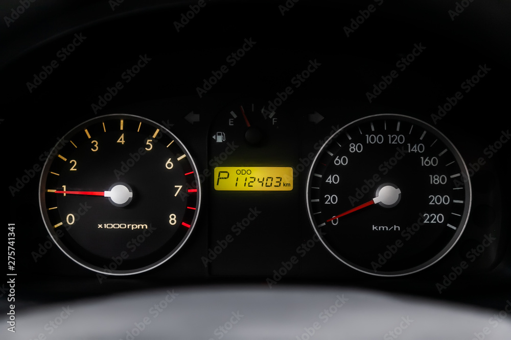 Car dashboard wuth red backlight: Odometer, speedometer, tachometer, fuel level, water temperature and more. Modern car interior: parts, buttons, knobs..