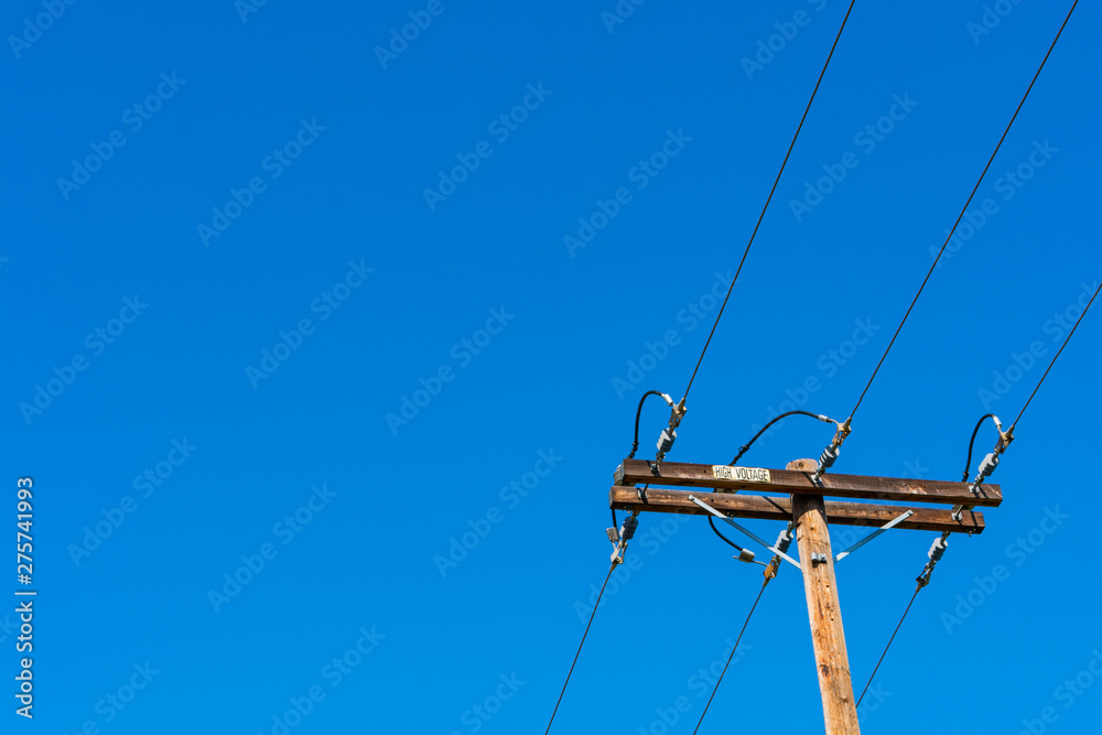 High voltage wooden utility pole (column or post) with parallel single-circuit lines in the blue sky