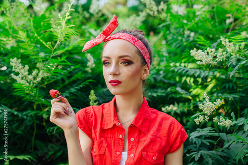 Beautiful young pin up girl with bright make up and fresh natural strawberry.