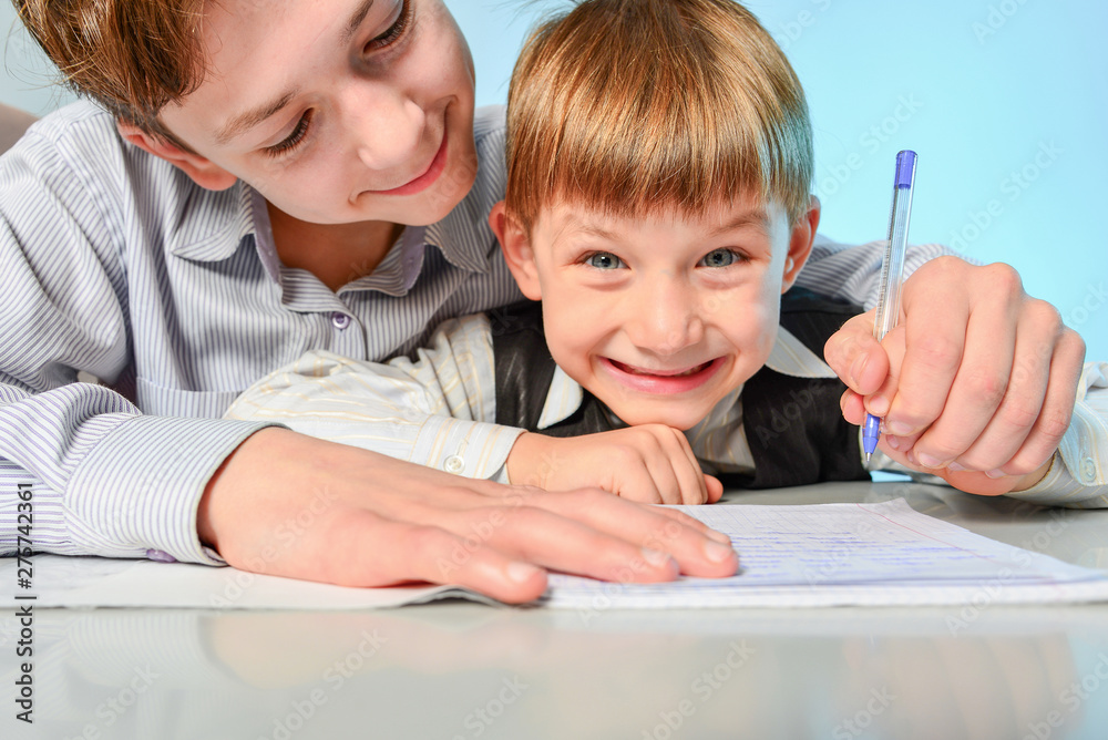 A high school student prepares a first grader in writing and preparing for school. Older brother teaches younger. A high school student prepares a first grader in writing and preparing for school. Older brother teaches younger.