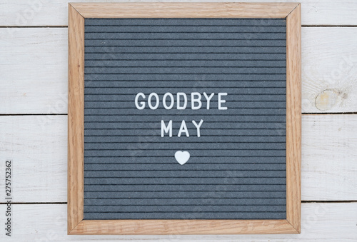 text in English goodbye May and a heart sign on a gray felt Board in a wooden frame