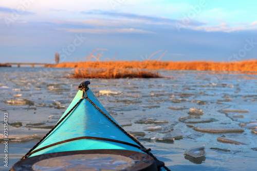 Bow (prow) of blue kayak among ice floes in winter or early spring river. Winter kayaking