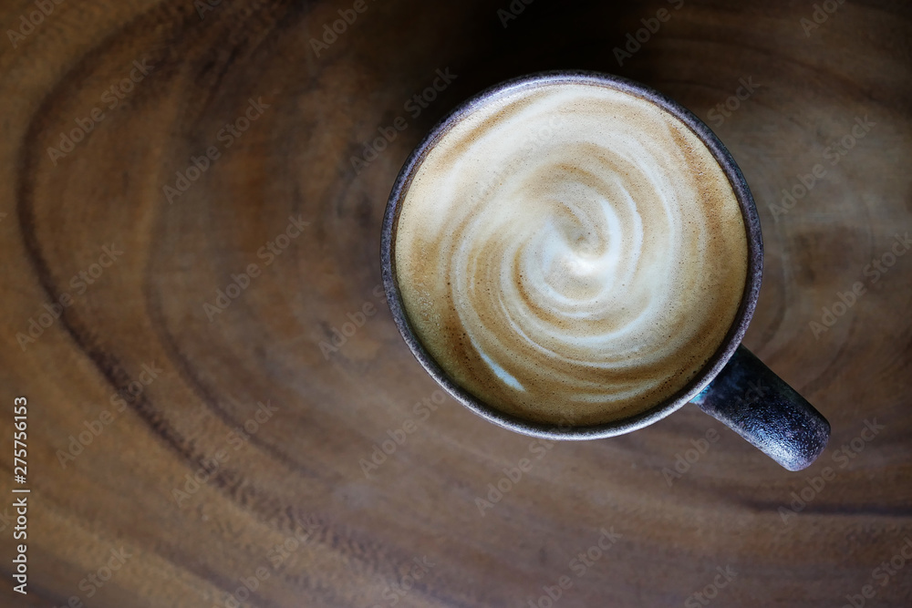 Φωτογραφία Top view of hot coffee cappuccino latte cup with spiral milk foam on wood texture table background