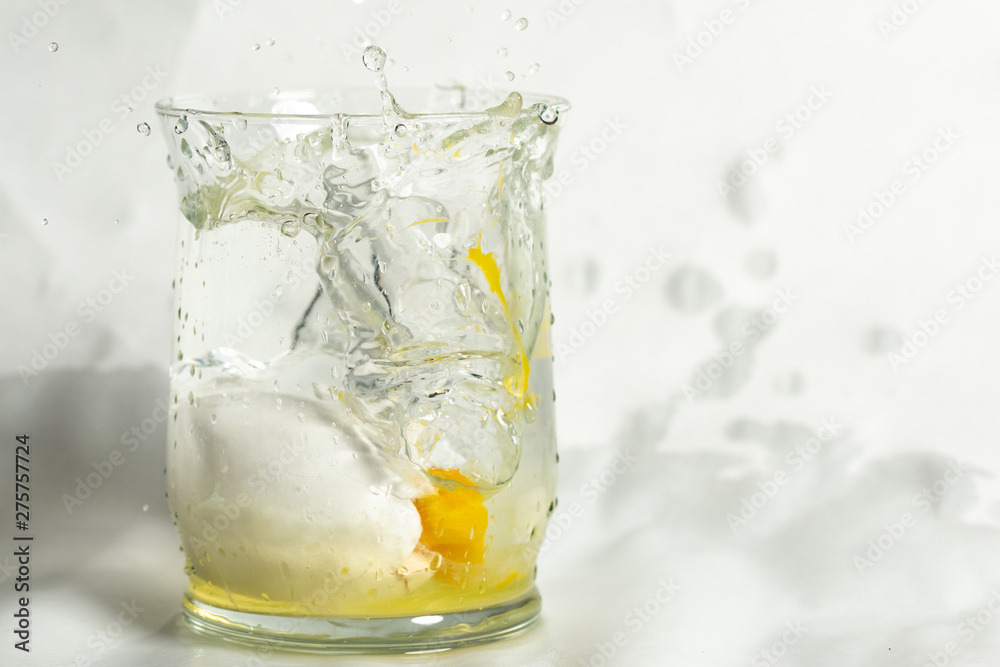 glass of water with ice and broken egg glass of water with ice and broken egg