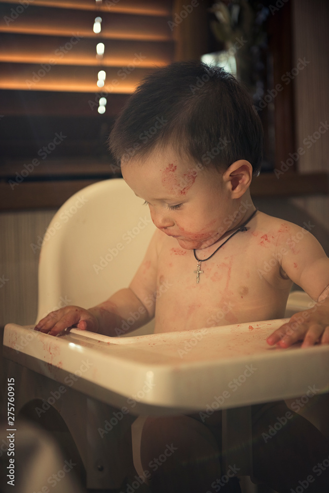 Young boy in a highchair smeared in strawberry juice. Young boy in a highchair smeared in strawberry juice.