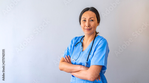 Portrait Of Smiling Female Doctor Wearing Scrubs With Stethoscope In Hospital Office. Portrait of young medical assistant with stethoscope on color background photo