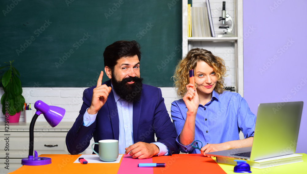 Portrait of couple university students. Exam in college. Young male teacher with female student over green chalkboard background. Teachers couple in classroom. Students and tutoring education concept. Portrait of couple university students. Exam in college. Young male teacher with female student over green chalkboard background. Teachers couple in classroom. Students and tutoring education concept.